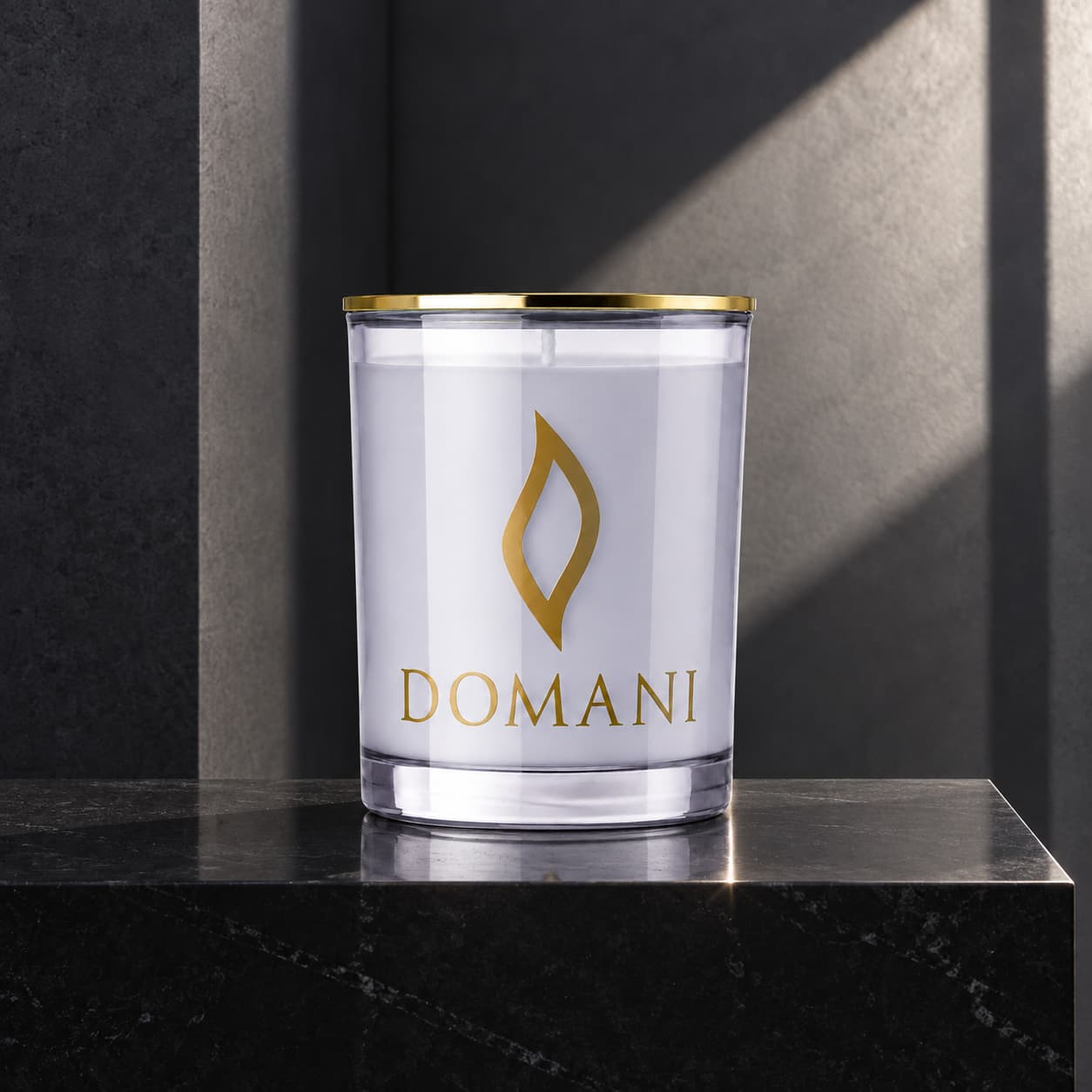 Domani bibliotheca candle in Sapphire glass, on a black stone plinth against charcoal architecture. Also available in the other three jar colors.