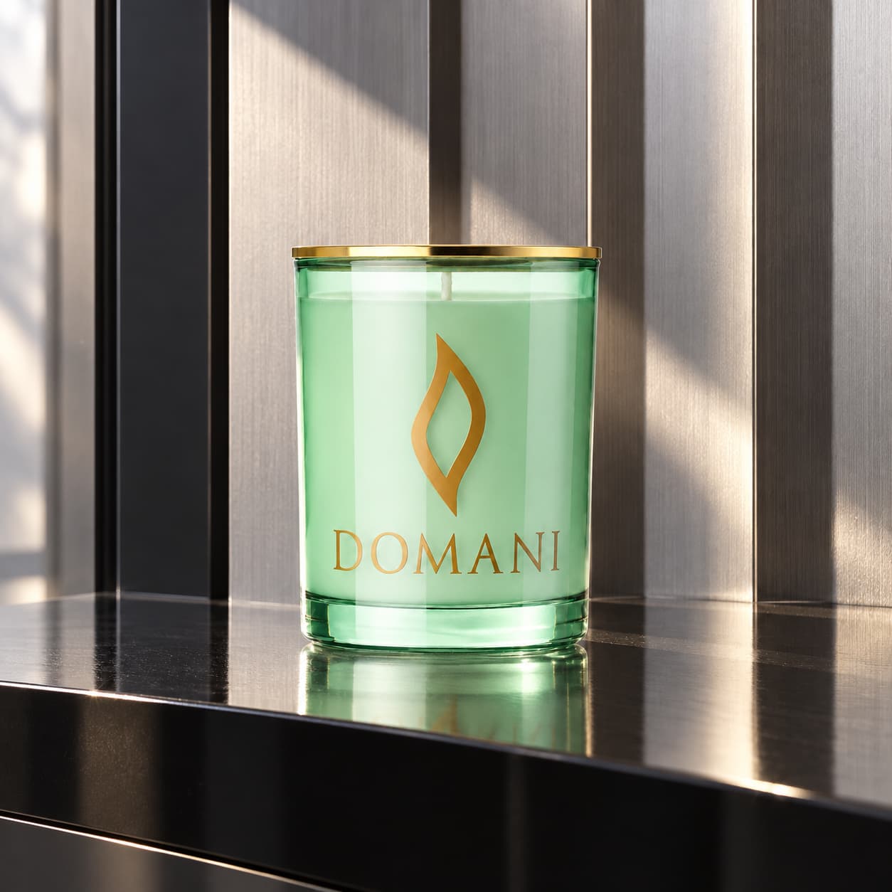Domani fifth avenue candle in Emerald glass, on black lacquer before brushed-silver architectural fins. Also available in the other three jar colors.