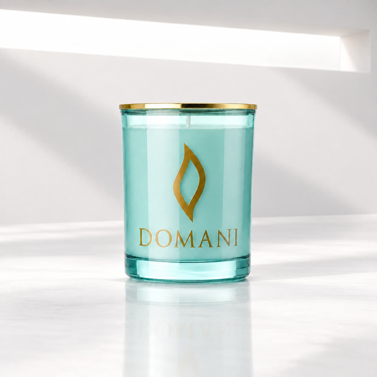 Domani lumina candle in Aquamarine glass, beneath a neutral-white light aperture. Also available in the other three jar colors.