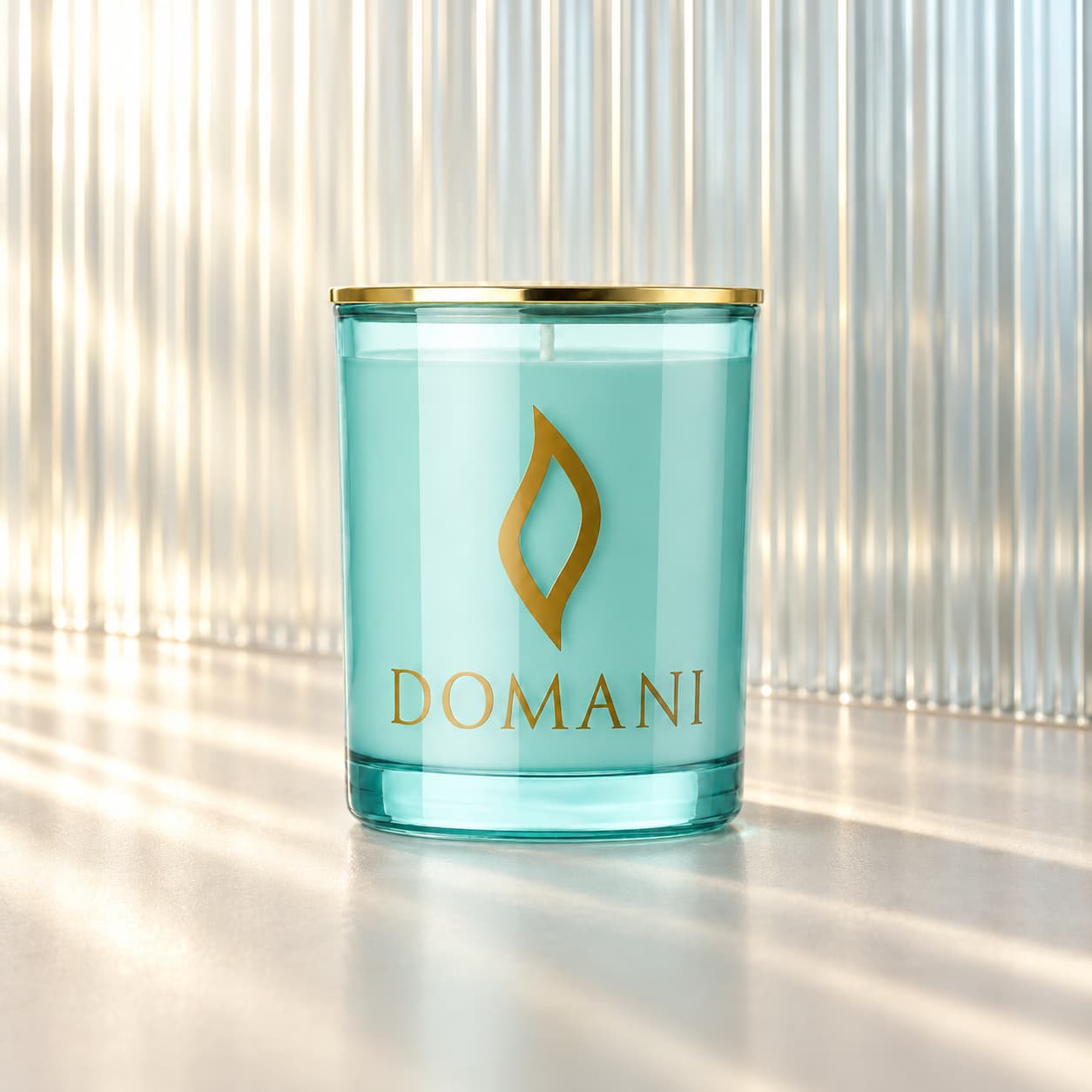 Domani reverie candle in Aquamarine glass, before a ribbed translucent-glass partition. Also available in the other three jar colors.