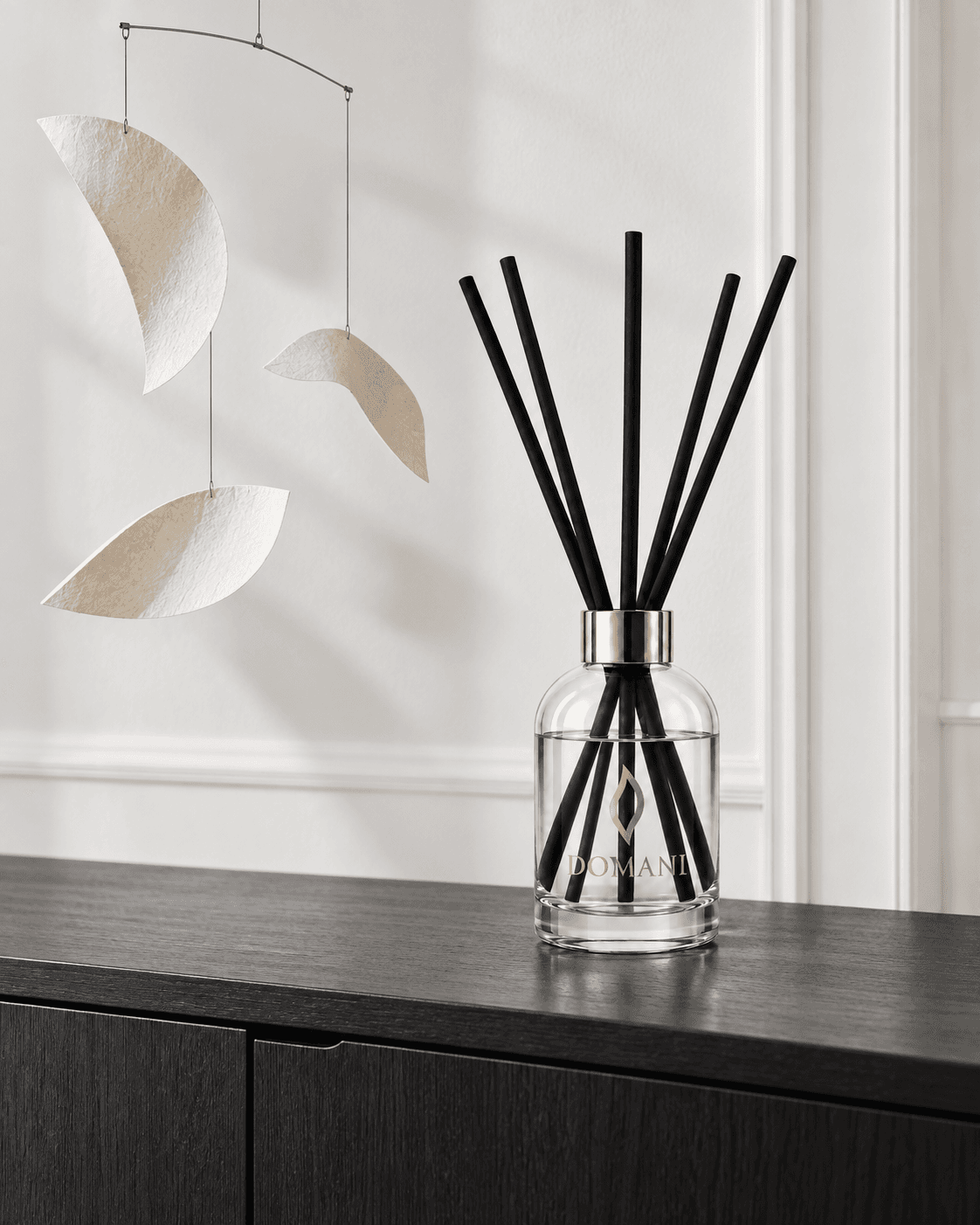 Three curved fibrous paper forms suspended from a fine balance bar and cords.