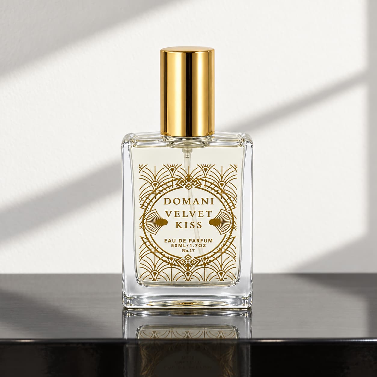Velvet Kiss 50 ml perfume with open gold artwork on a black console in window light.