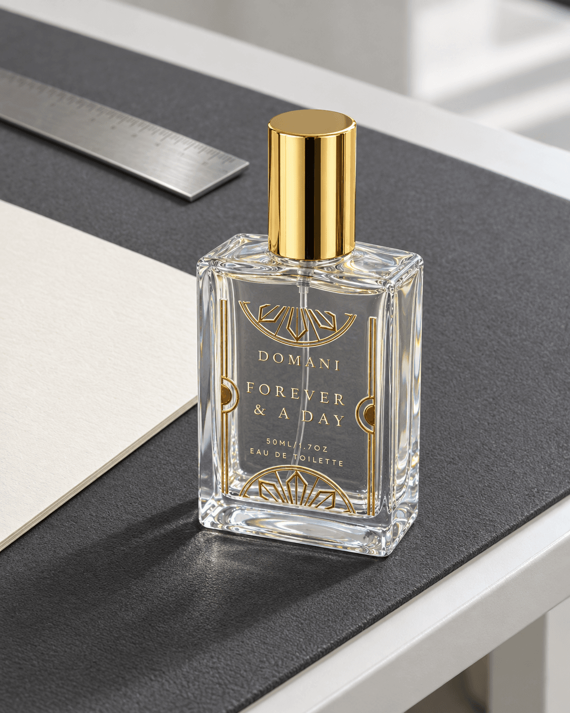 An elevated three-quarter view of the complete Forever & A Day 50 ml eau de toilette on a drafting table beside white paper and a steel straightedge.