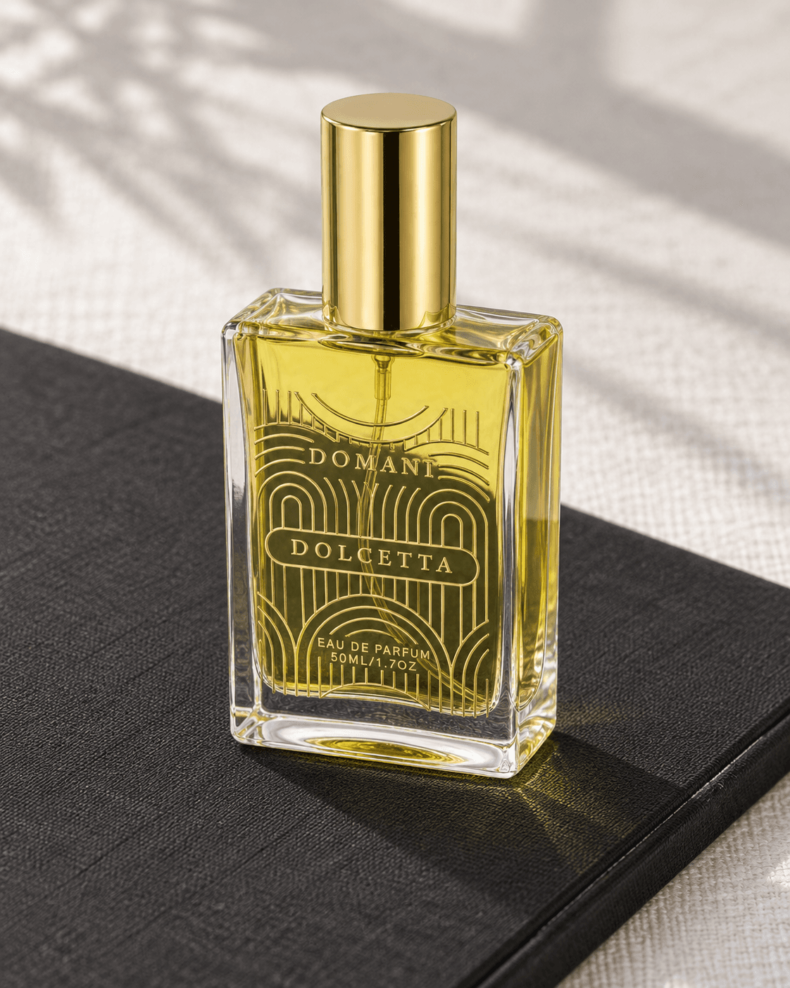 Domani Dolcetta 50 ml bottle viewed from an elevated three-quarter angle on a black cloth-covered portfolio over pale linen.